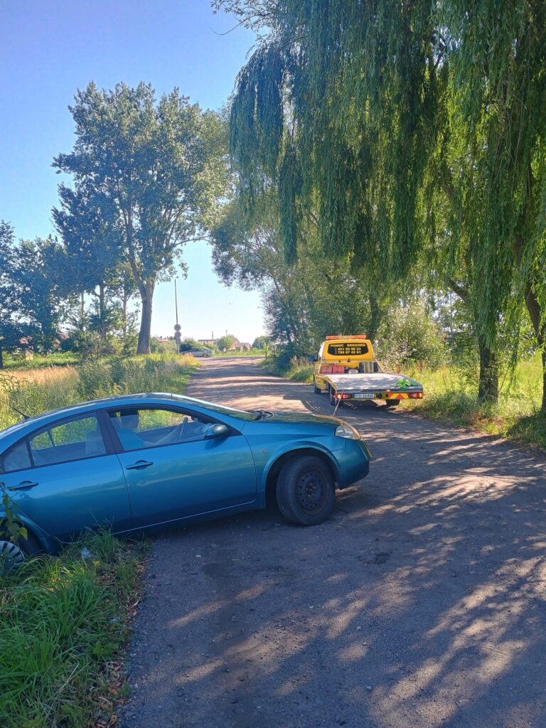 Pojazd pomocy drogowej Słubice w akcji, holujący zepsuty samochód na drodze.